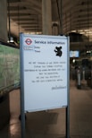 A service information board at a subway station displays a message of solidarity with Australia, expressing sorrow for the loss of life and devastation. The board includes social media handles and a shadow-like illustration of a koala.