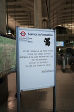A service information board at a subway station displays a message of solidarity with Australia, expressing sorrow for the loss of life and devastation. The board includes social media handles and a shadow-like illustration of a koala.