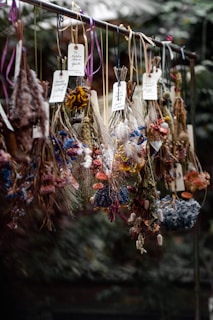 Hand-tied bundles of dried herbs hanging against a soft, botanical print backdrop.