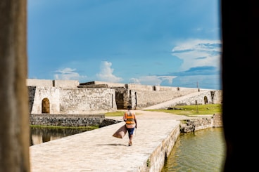 man walking on pier under blue sky