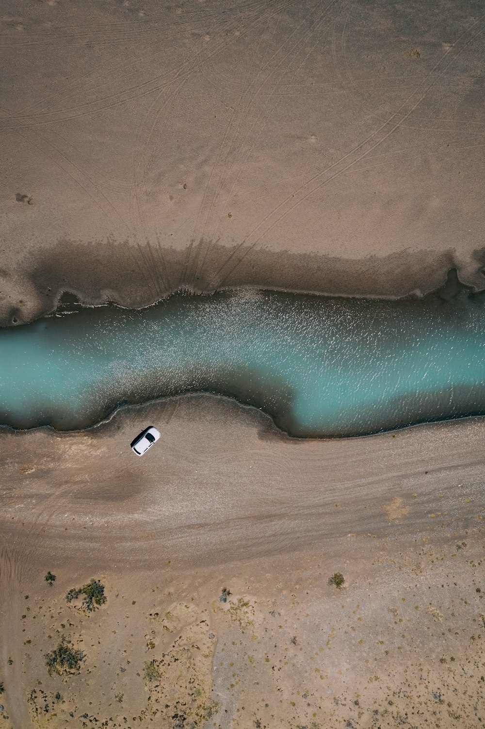 Vista aérea de un vehículo blanco cerca del cuerpo de agua