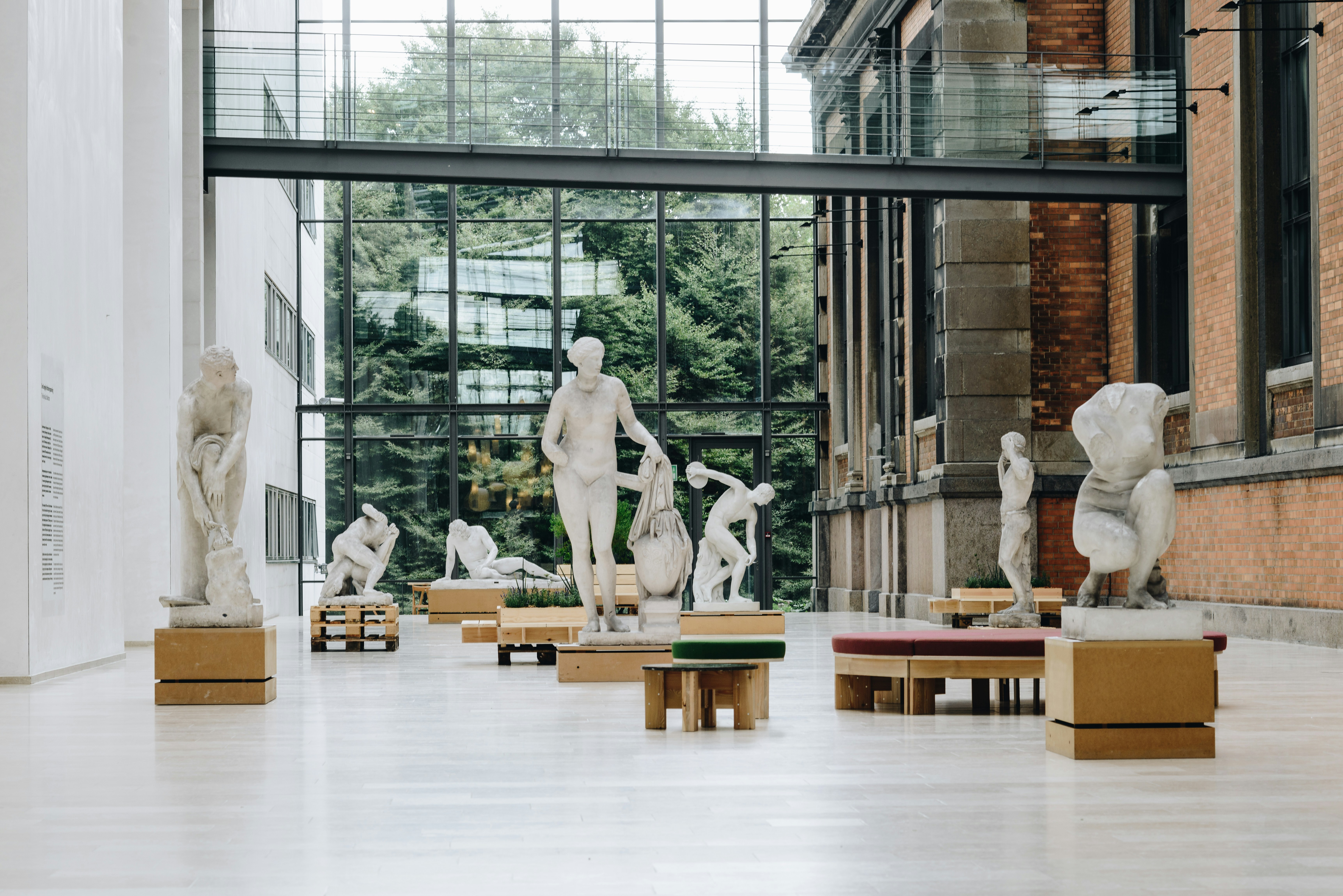 white marble sculpture gallery hall with a windowed wall exposing greenery from outside