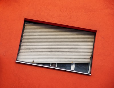 gray venetian blind hanging on a window tilted teams background