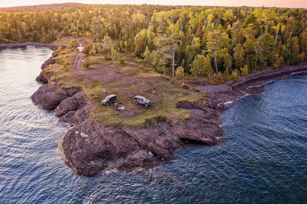 two vehicles on cliff facing body of water