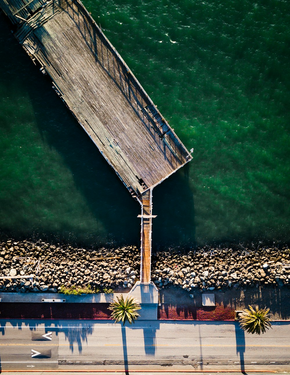 roadway beside brown wooden dock in aerial photography