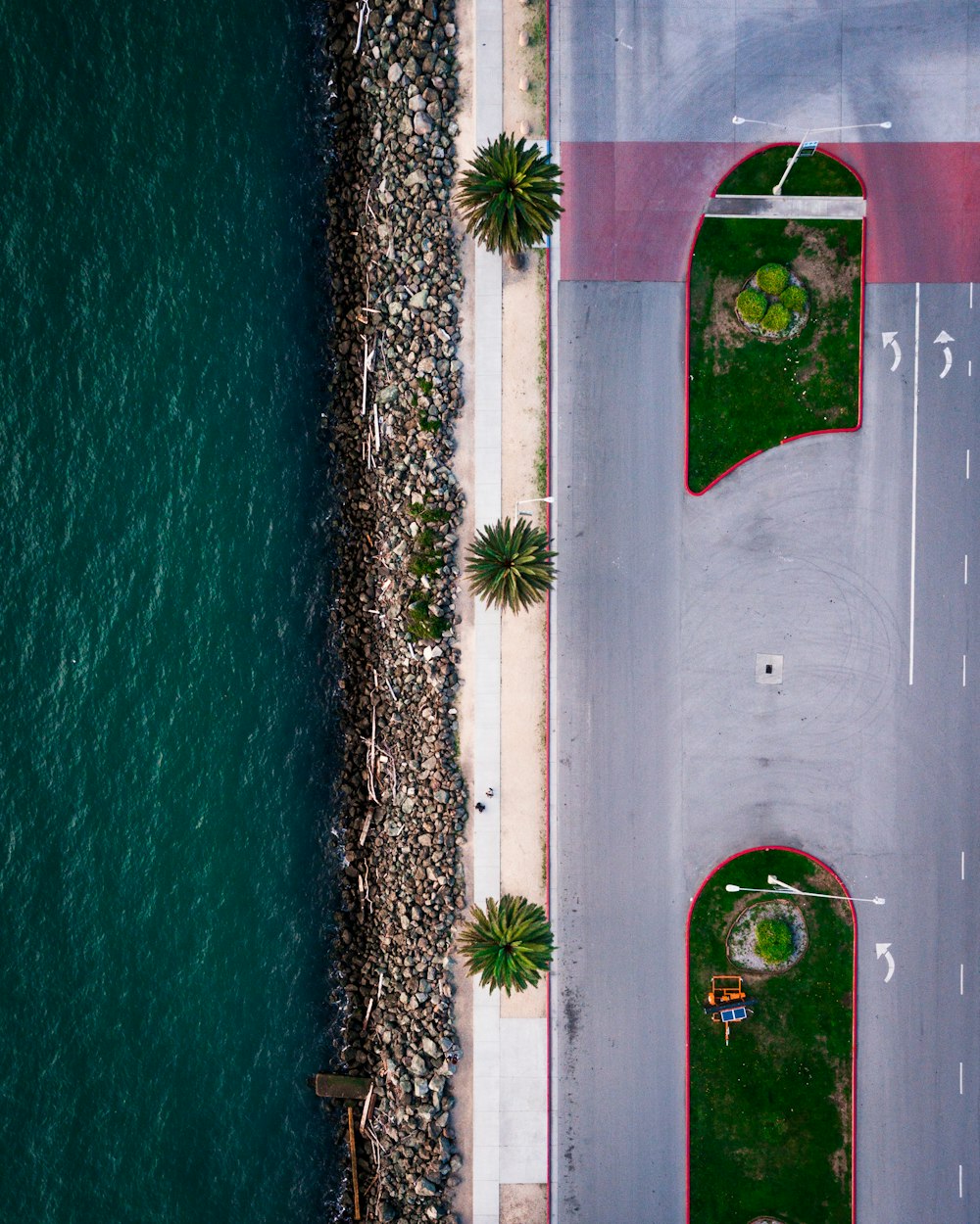 an aerial view of a road next to a body of water