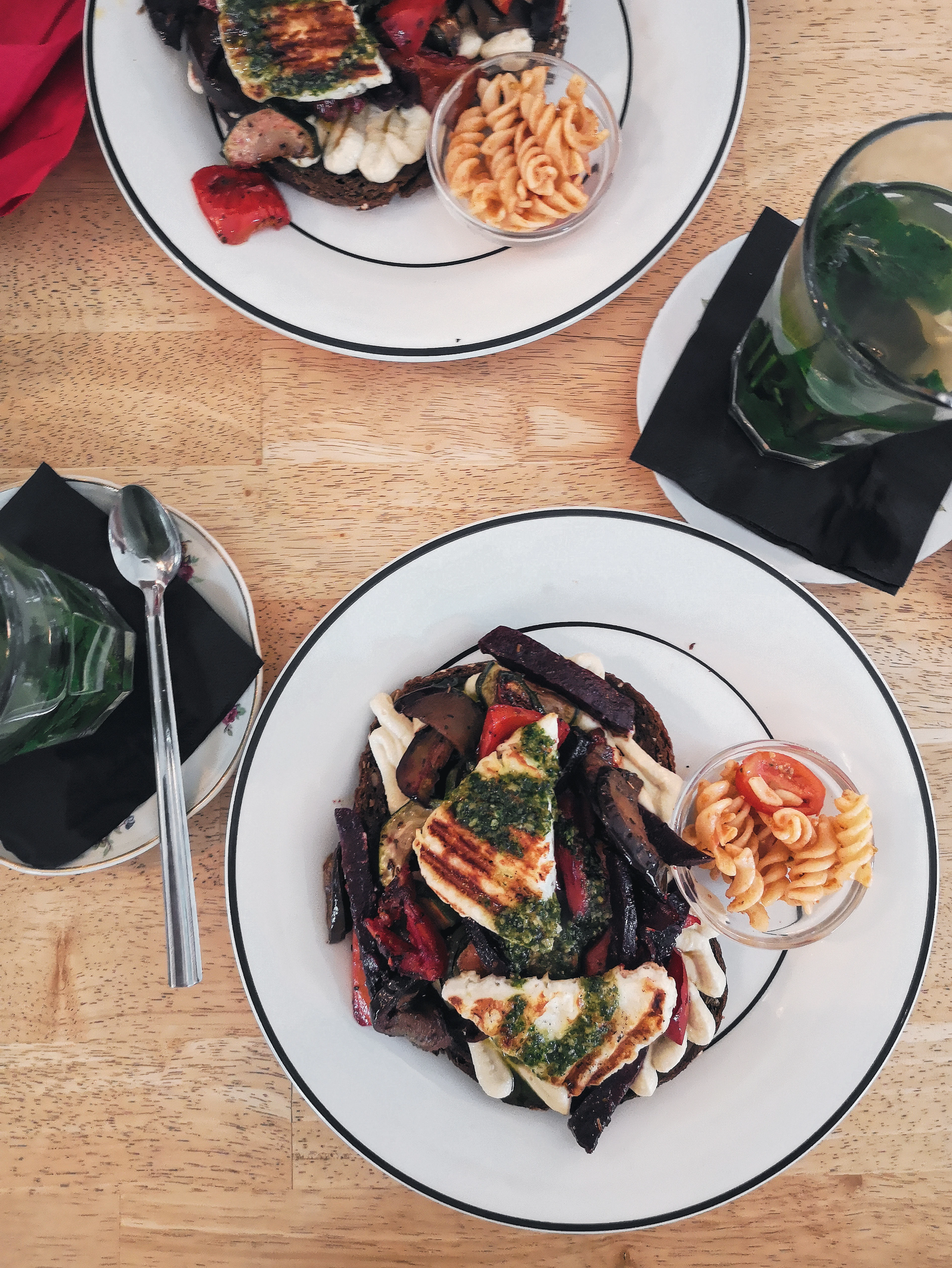 Grilled halloumi with charred vegetables on a plate, olives and bread alongside