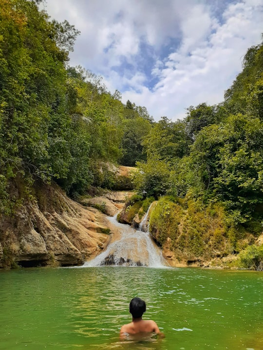 topless man on calm body of water during daytime in Malang Indonesia