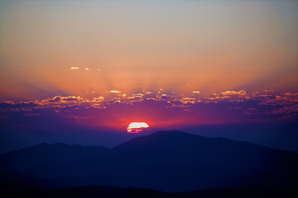 the sun is setting over a mountain range