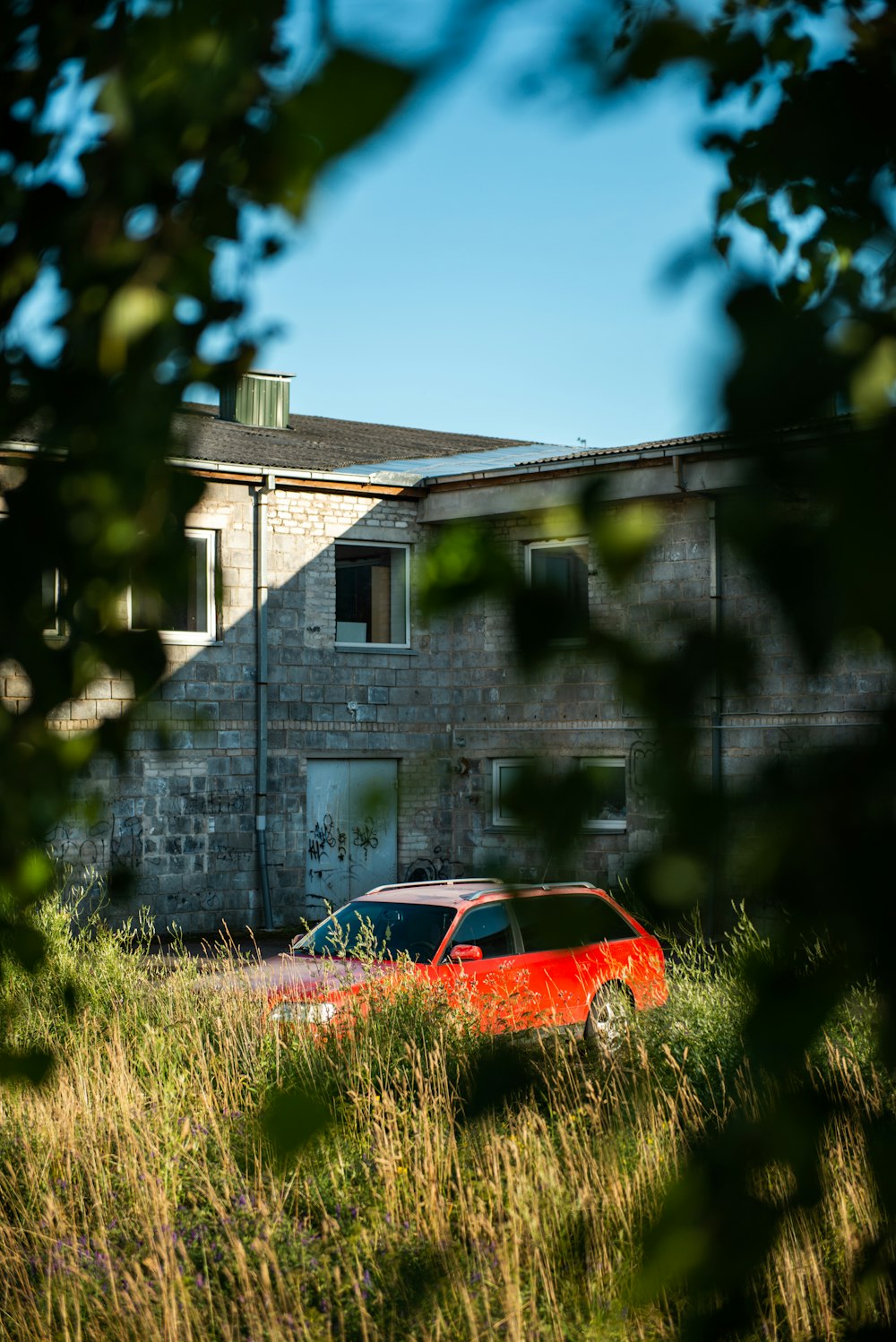 orange vehicle beside building during daytime