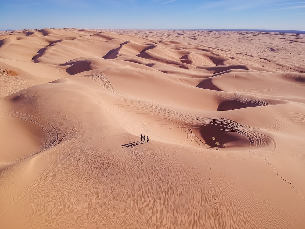 昼間、砂漠の砂の上に立つ3人