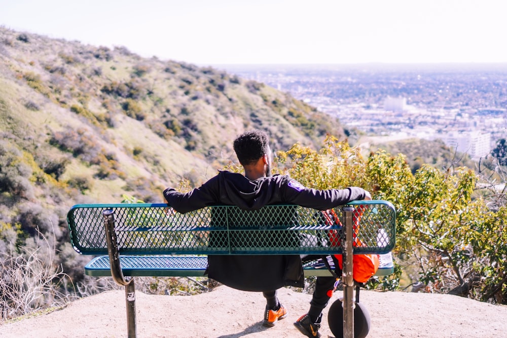 man wearing black jacket sitting on bench