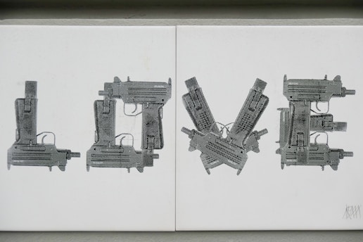 The image consists of the word 'LOVE' spelled out using illustrations of guns. Each letter is formed by creatively arranging the silhouette of a gun to represent a letter. The color scheme is monochromatic with varying shades of gray.