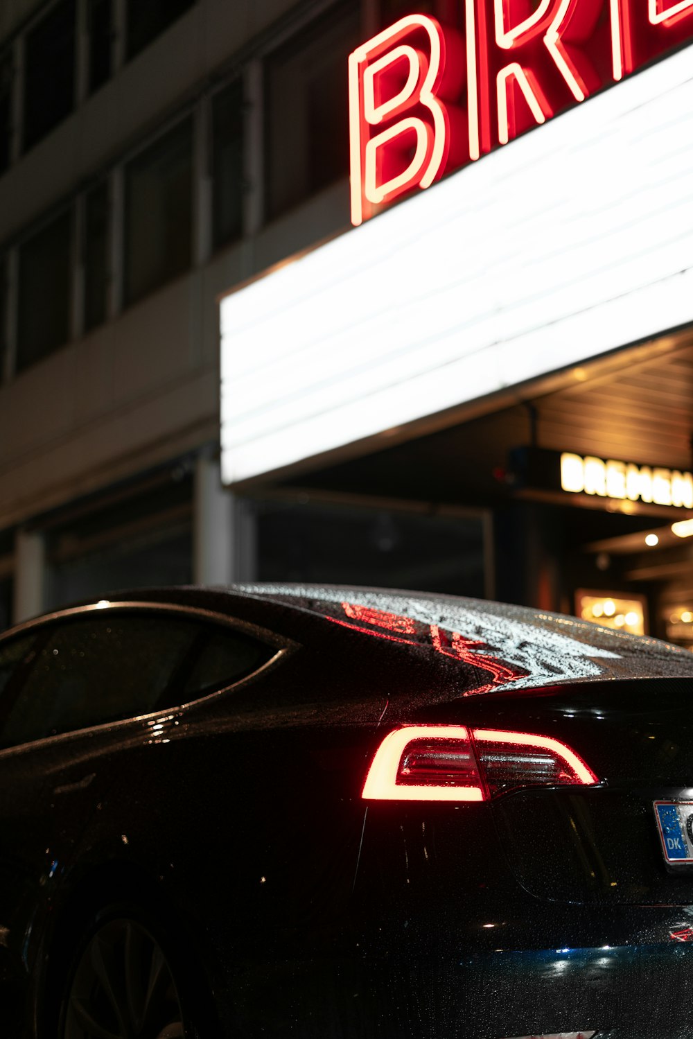 black car in front of building with neon sign