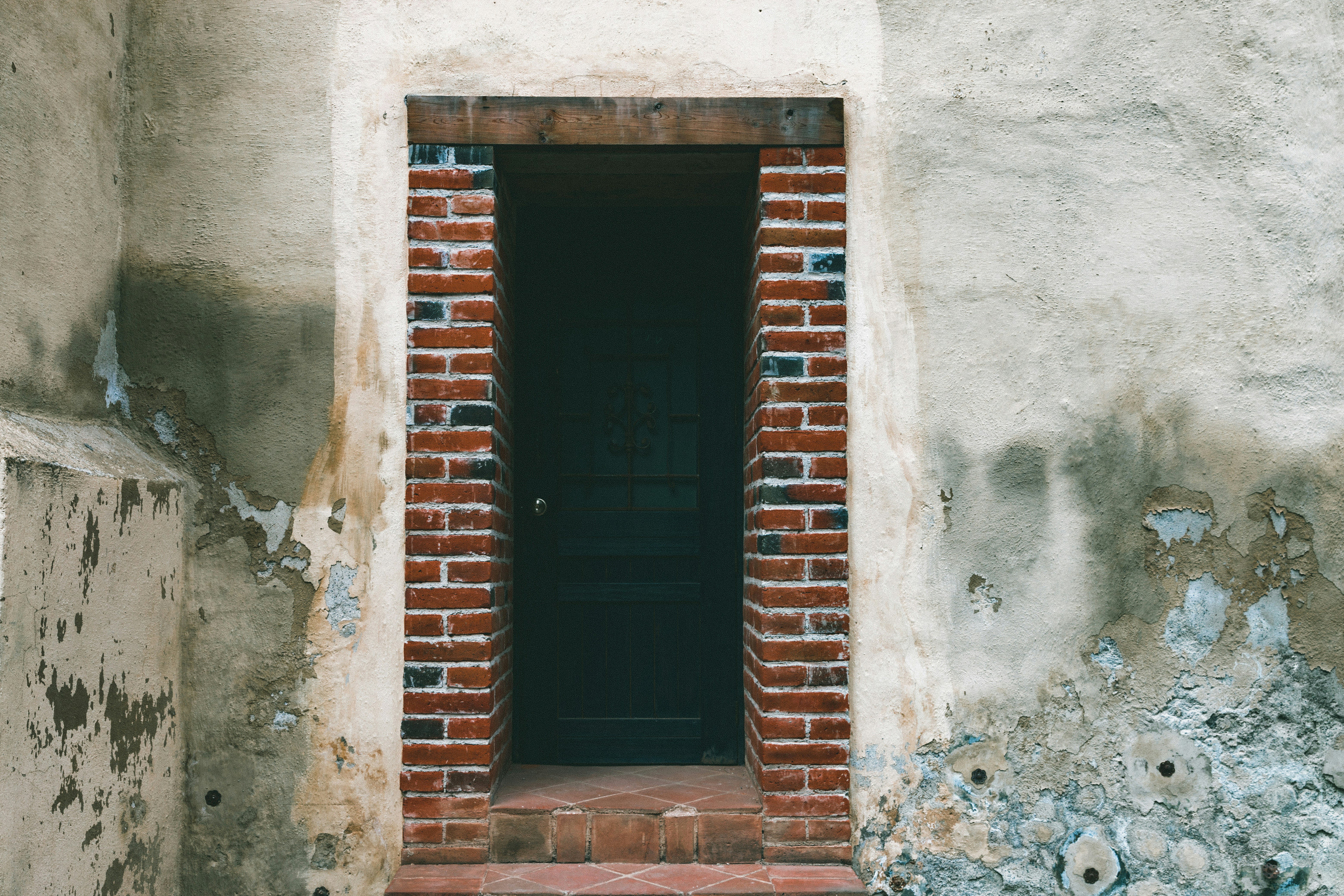 white concrete building showing closed black wooden door