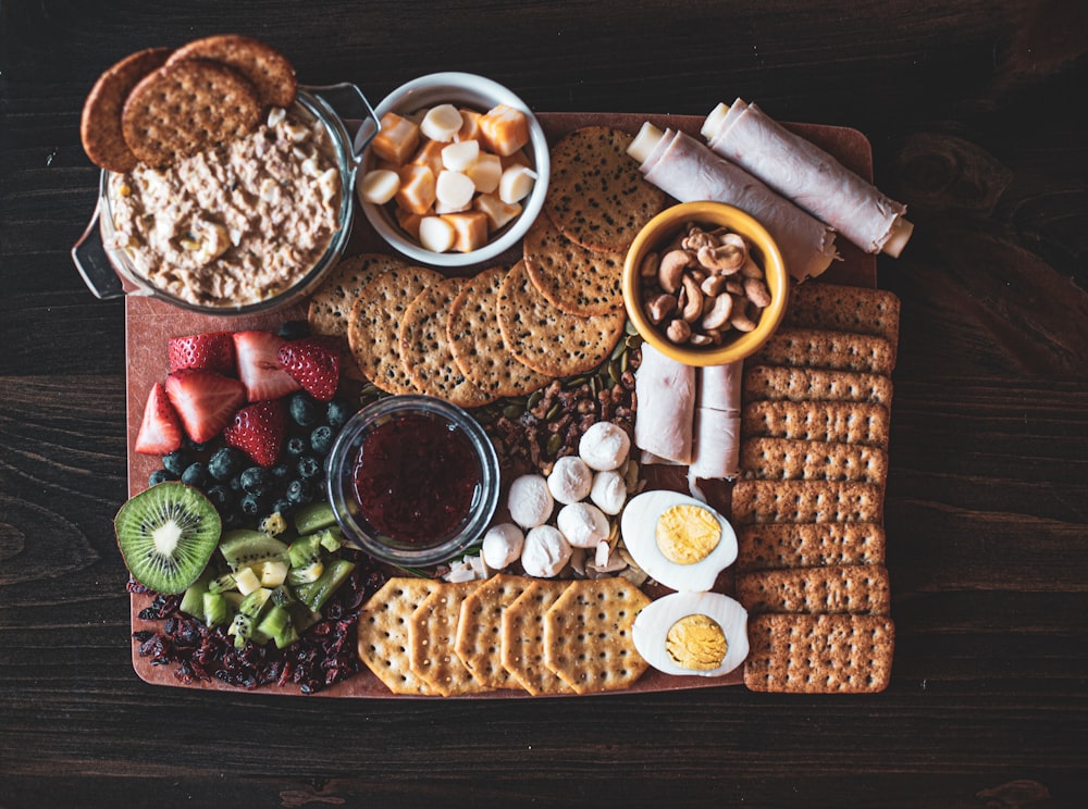 crackers near sliced strawberry, kiwi, and blueberry fruits beside sliced boiled eggs