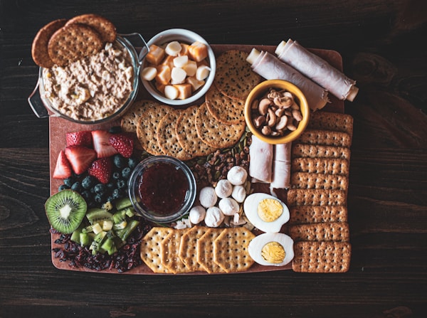 Crackers near sliced strawberry, kiwi, and blueberry fruits beside sliced boiled eggs