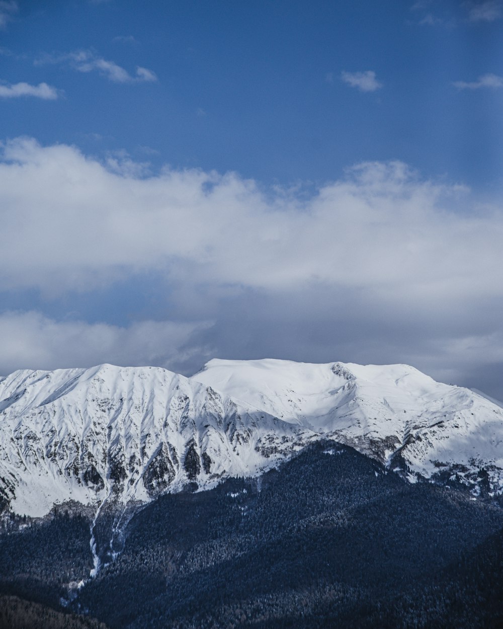 aerial photography of summit of mountain covered with snow under white and blue sky