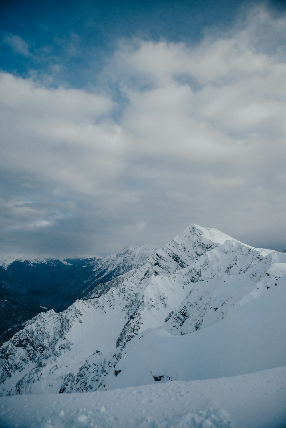 aerial photography of summit of mountain covered with snow under white and blue sky