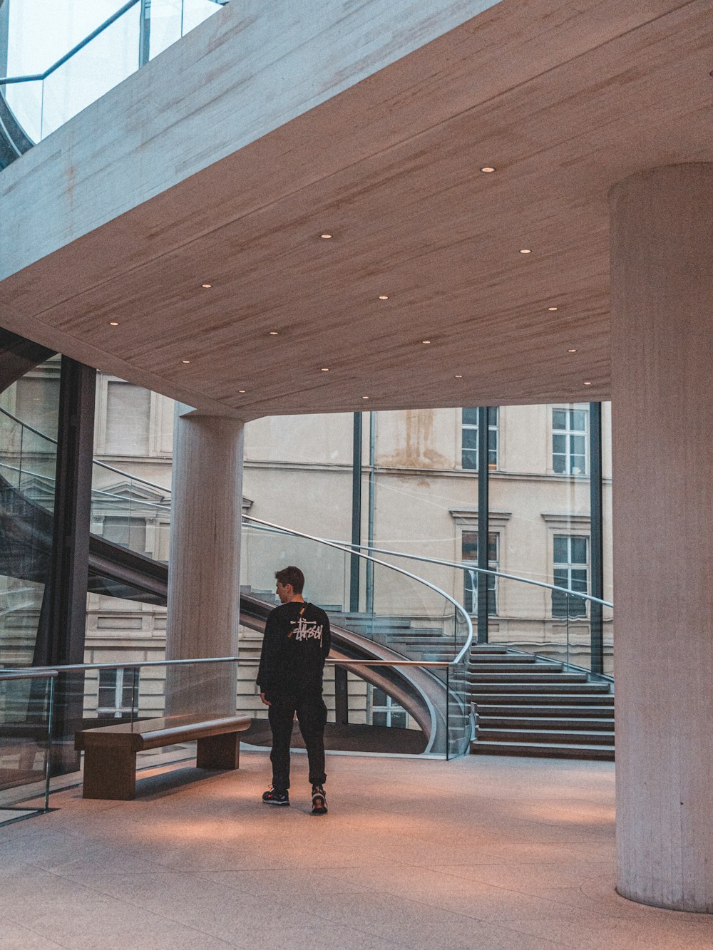 man standing near bench and stairs inside building