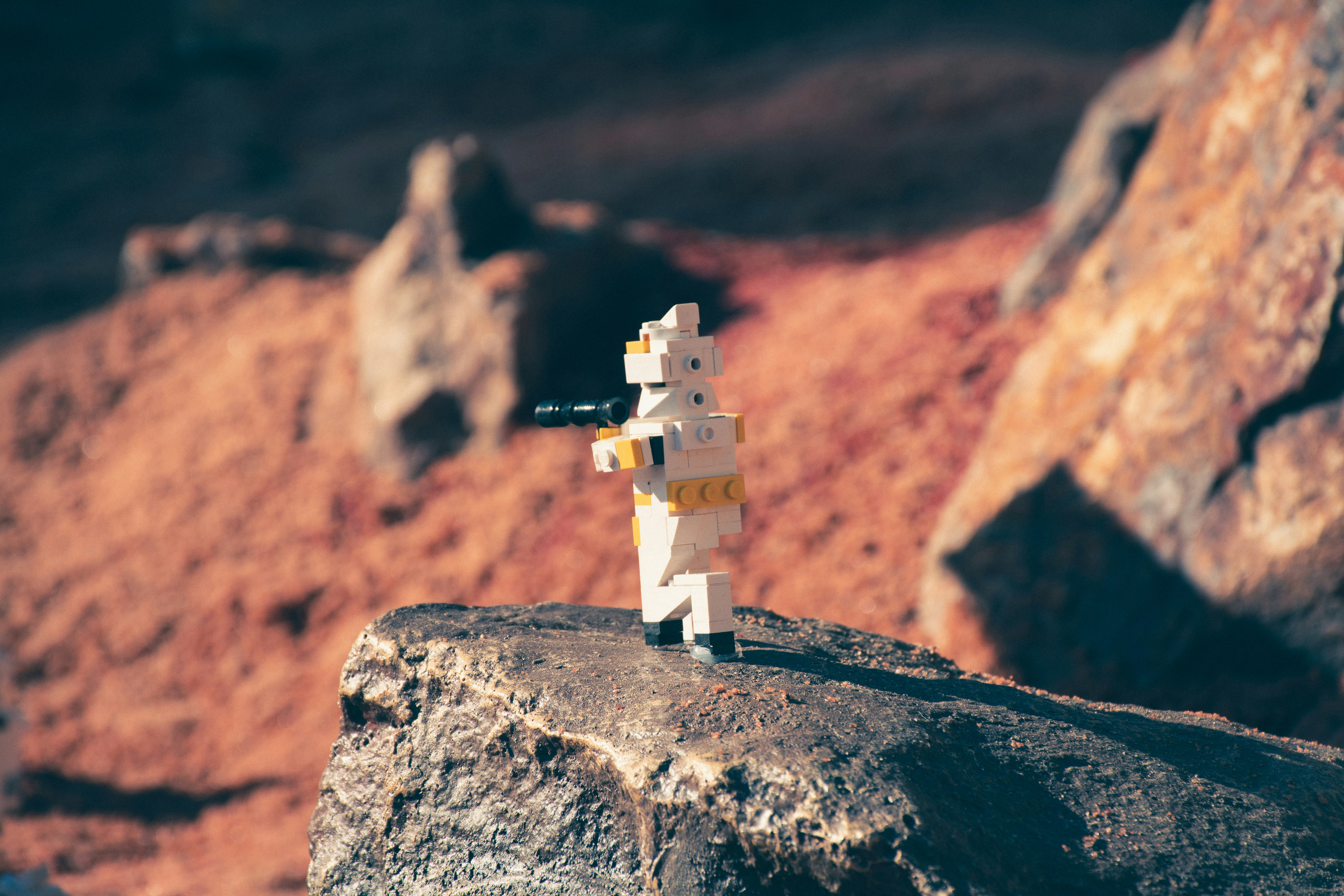 white and yellow Lego character figurine on black rock