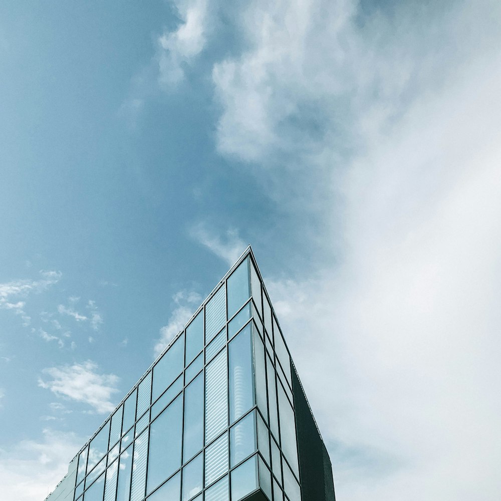 low-angle photography of blue glass walled high-rise building under blue and white sky