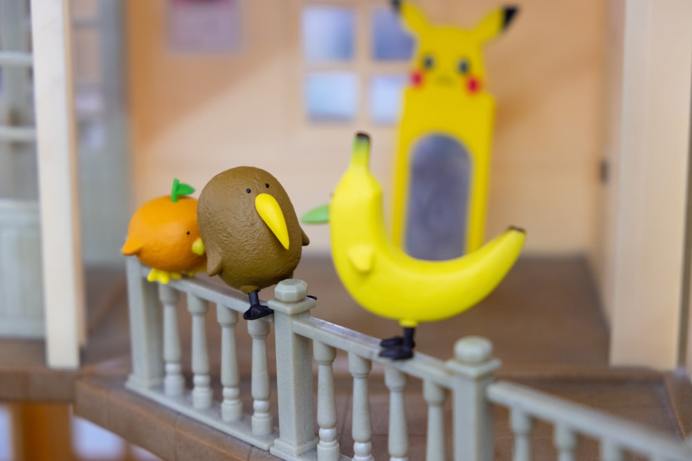 macro photography of three assorted-color toys on fence