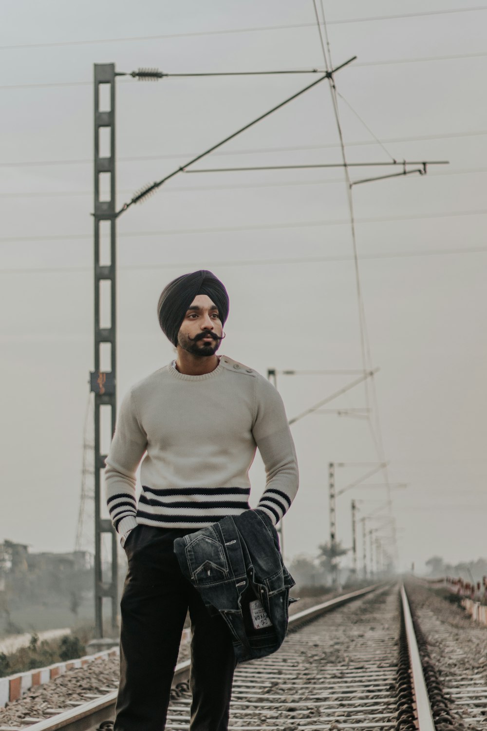 man walking along a train railway during daytime