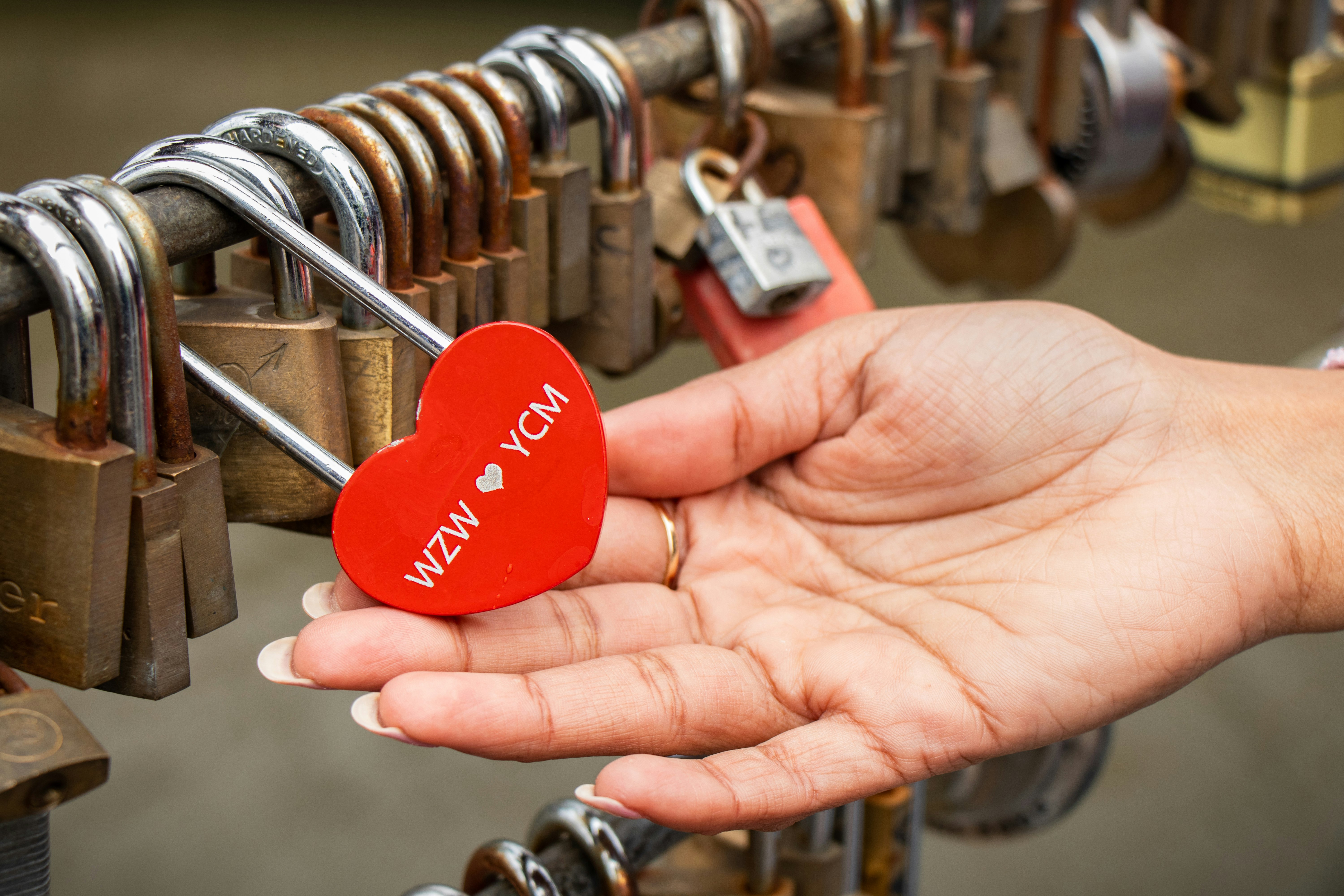 woman holding red heart padlock locked beside locked padlocks on bar