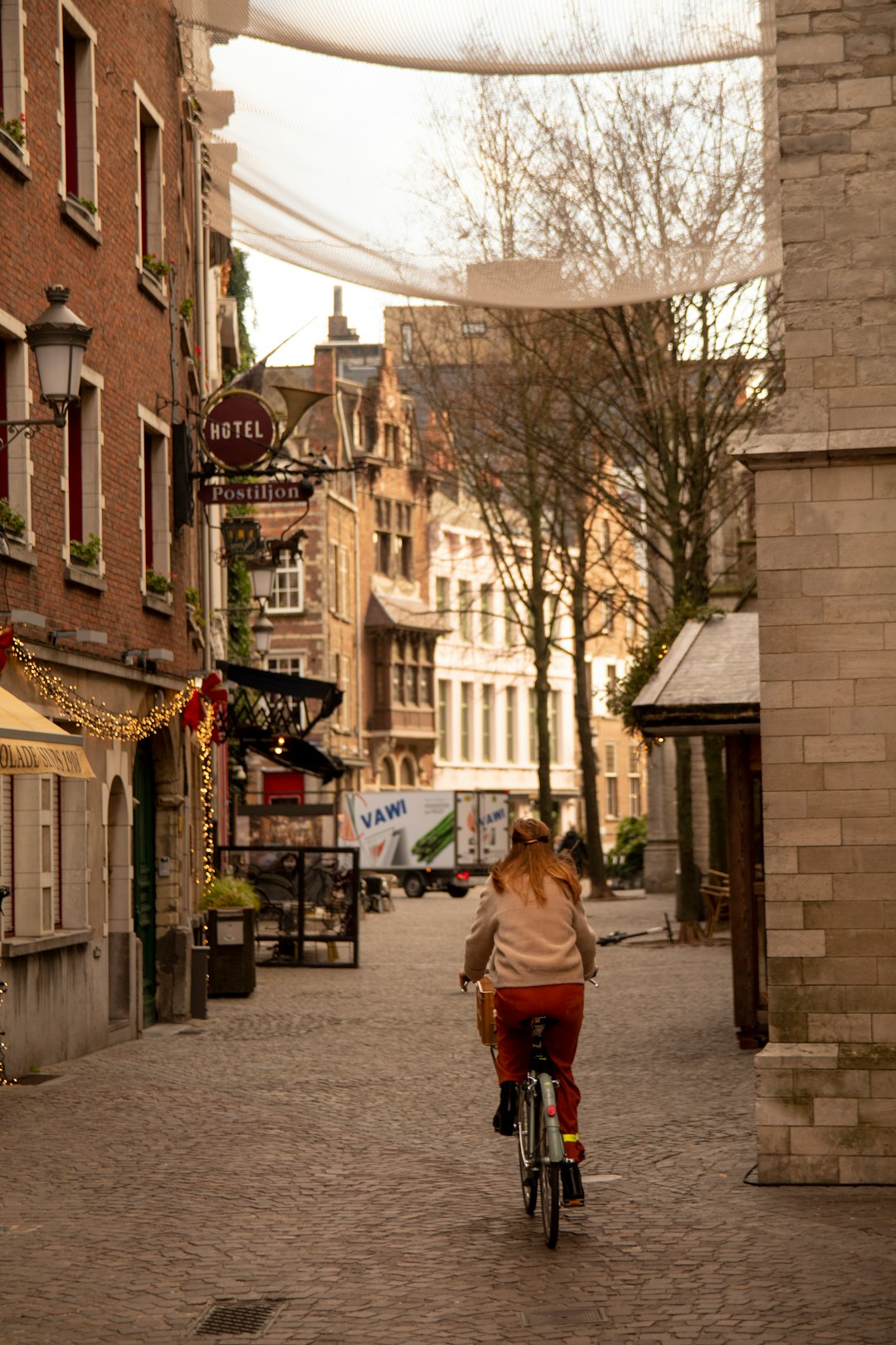 woman biking on road between houses and buildings during daytime