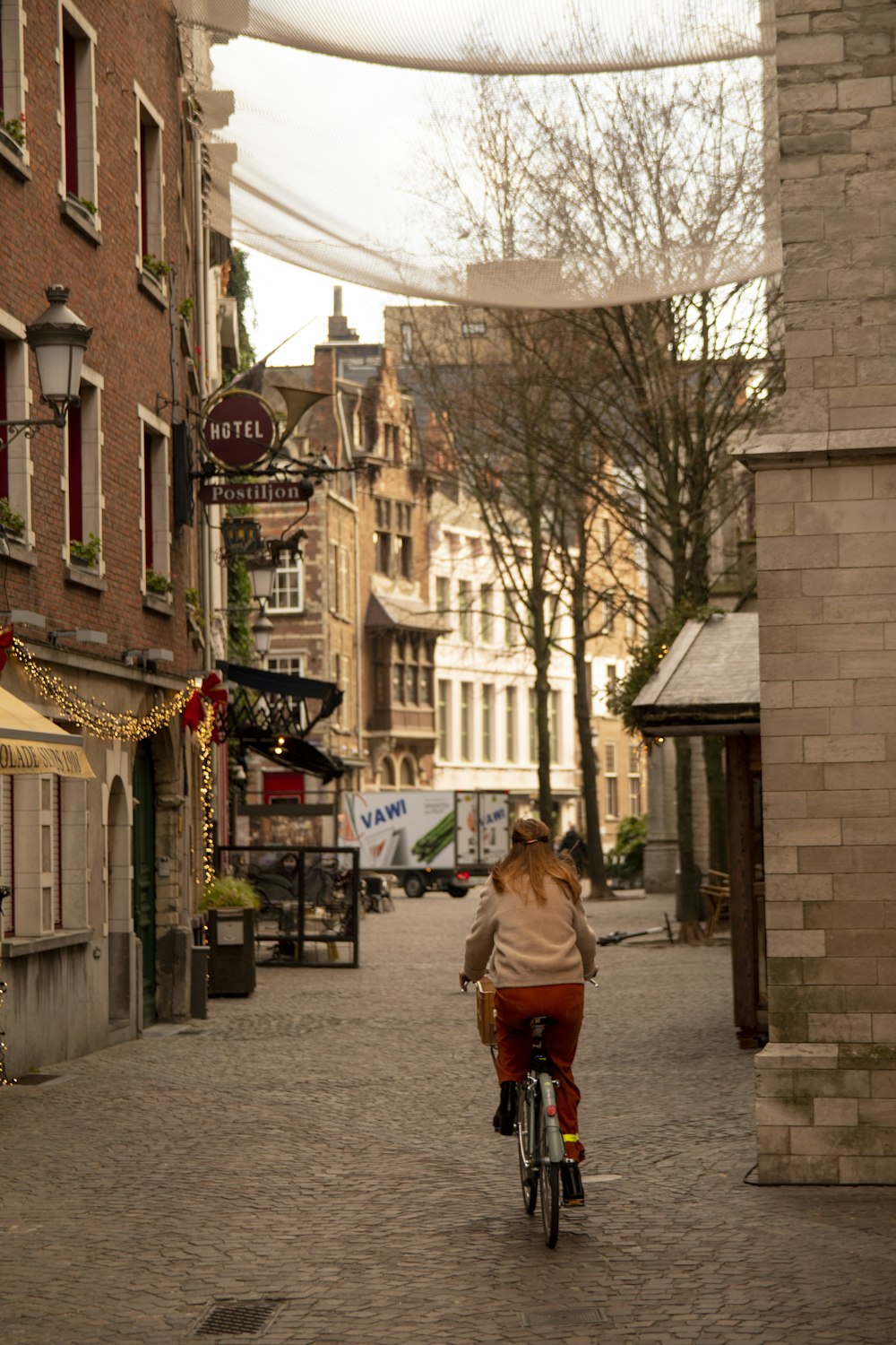 woman biking on road between houses and buildings during daytime