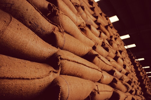 Stacks of neatly packed rice and grain sacks in a warehouse setting.