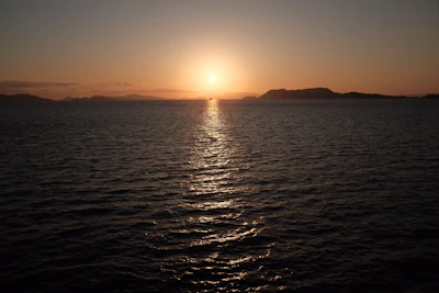Sunset casting warm light over the island's hills and the calm sea beyond
