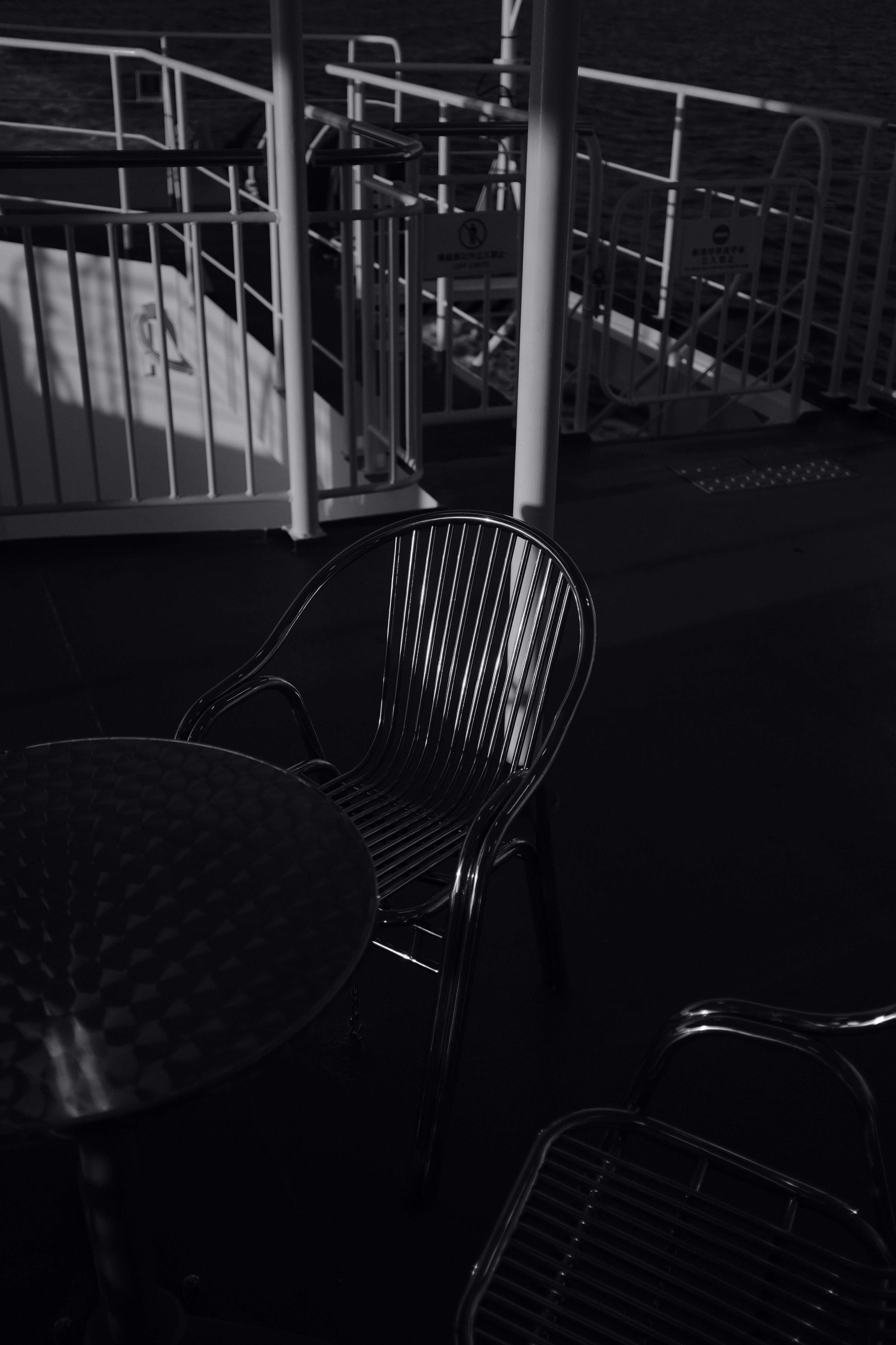 grayscale photography of metal chairs near table