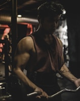 Focused man doing disciplined bench press with a shadowy, modern gym background.
