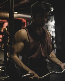 Athlete mid-clean with intense focus in a gym lit by red and white lights.