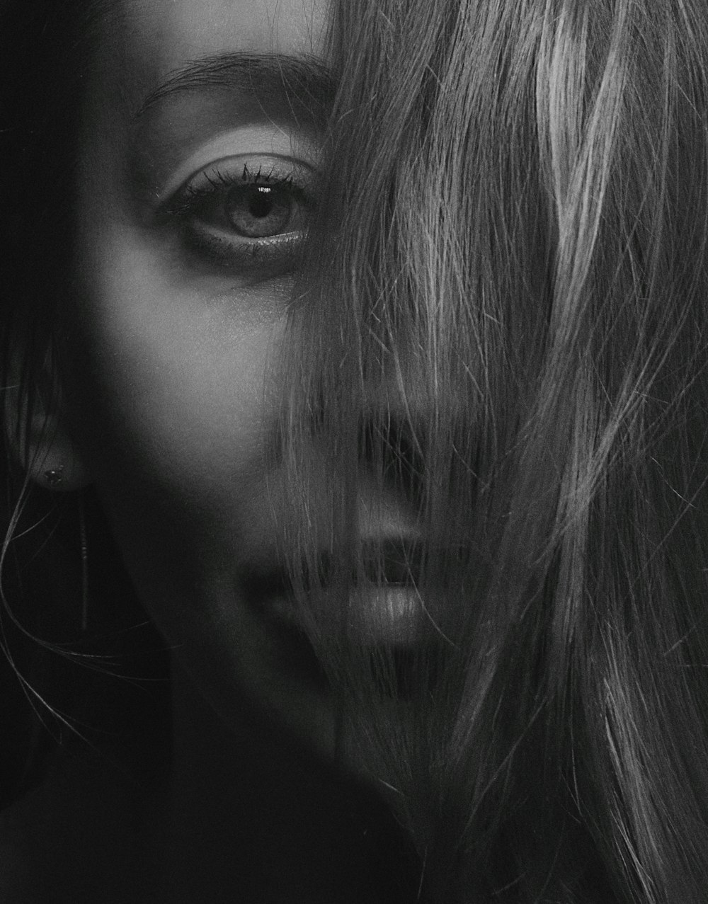 portrait photography of woman covering half face using her hair