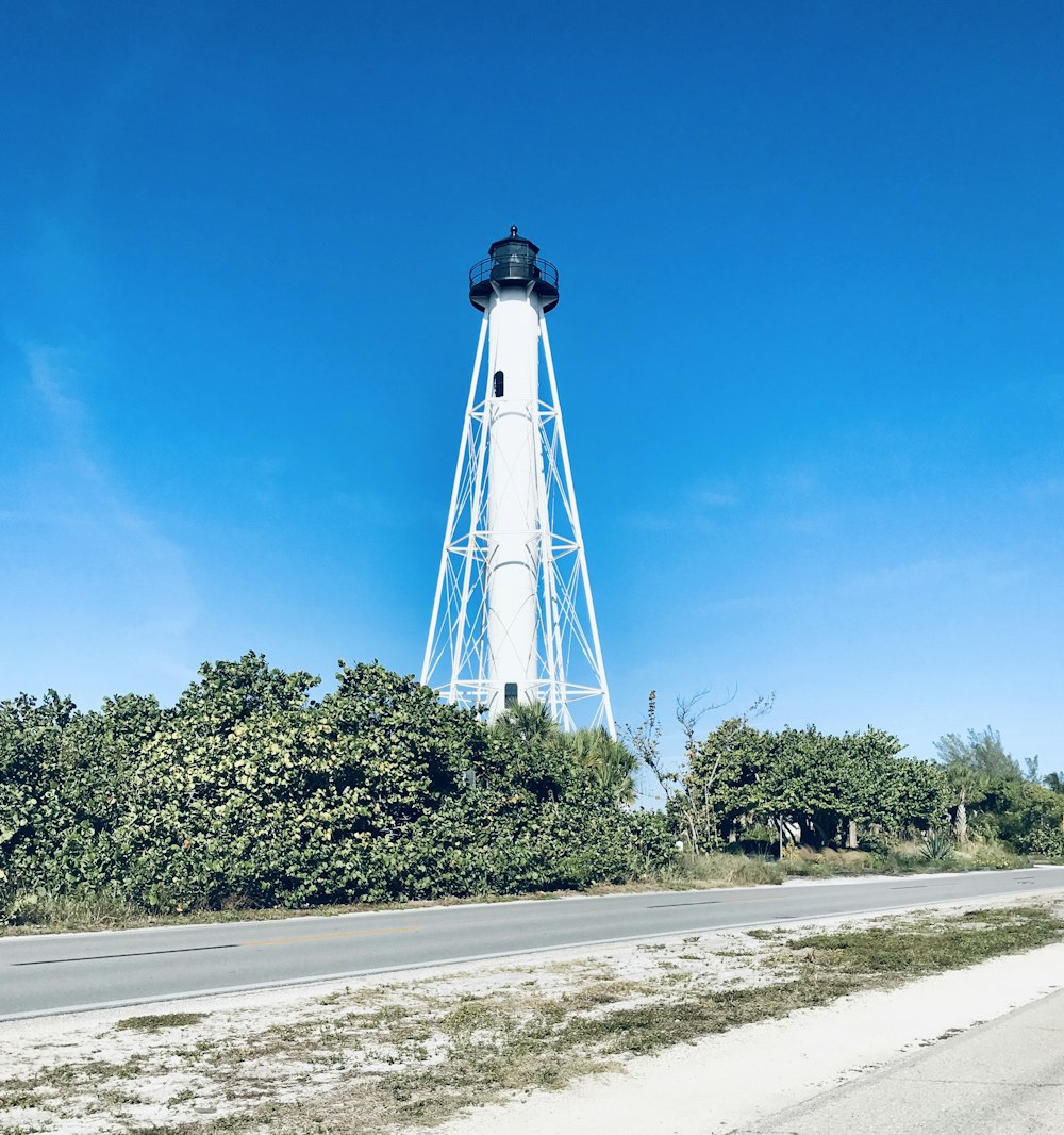 lighthouse beside trees and road during day