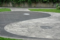A close-up of a yin yang symbol carved in smooth stone resting on a bed of green moss.