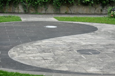 A close-up of a yin yang symbol carved in smooth stone resting on a bed of green moss.