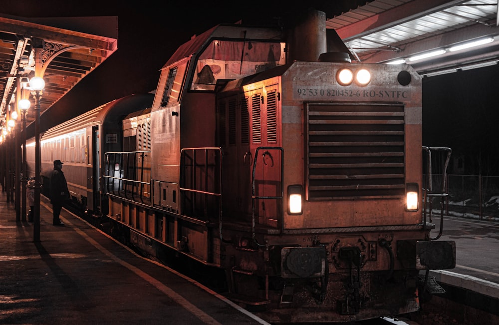 person standing beside train at the train station during night