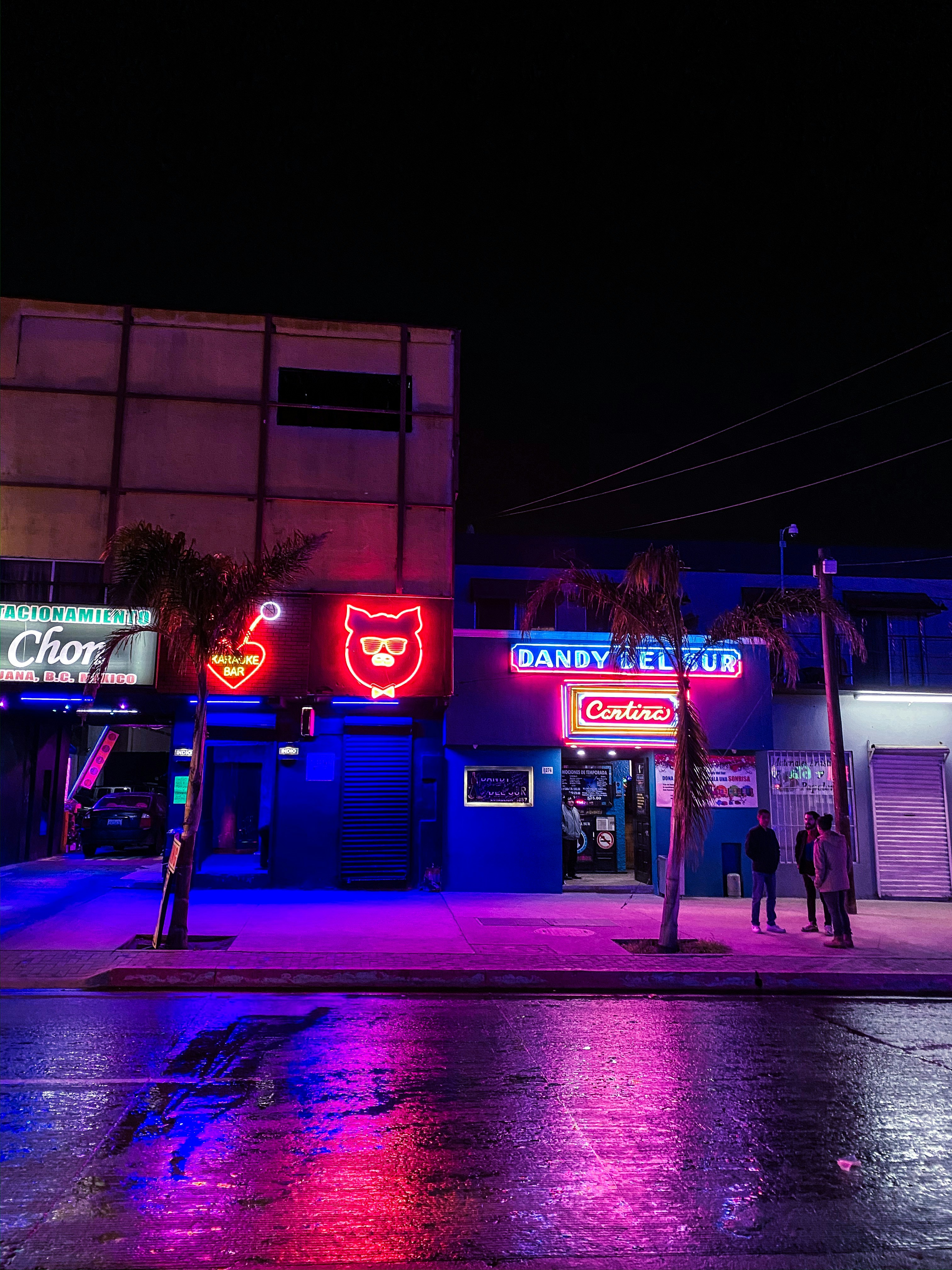 Neon lit street at night with colorful reflections on wet pavement
