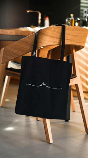 A sleek leather tote bag hanging on a modern chair in a cozy room.