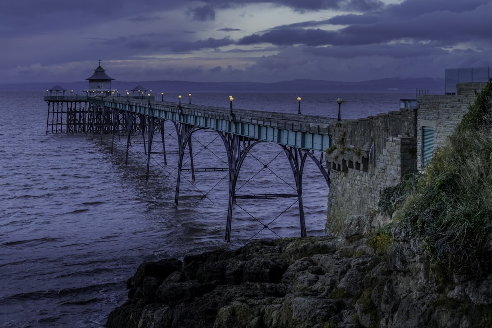 Photographie aérienne d’un pont en acier vert regardant la mer bleue sous le ciel bleu et blanc