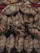 A close-up view of a pile of baked goods, likely empanadas, featuring a golden-brown crust with slightly darker patches. Each pastry is folded and crimped at the edges, showcasing an artisanal and homemade appearance.