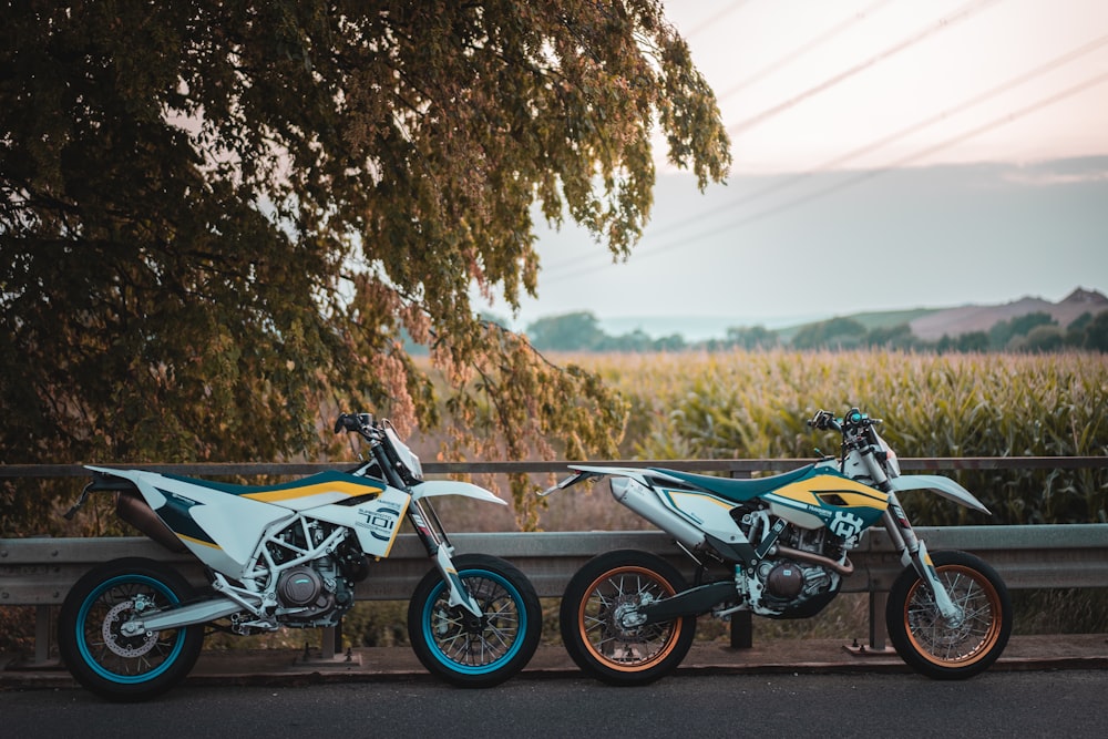 two motocross dirt bike parked near fence during near tree