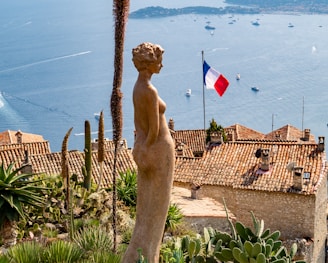 woman brown statue with view of France flag during daytime