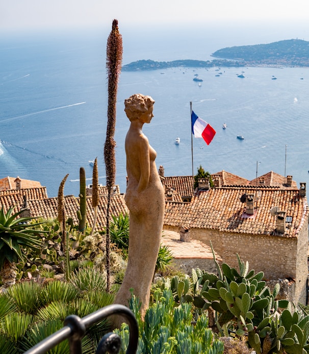 woman brown statue with view of France flag during daytime