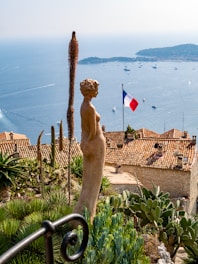 woman brown statue with view of France flag during daytime