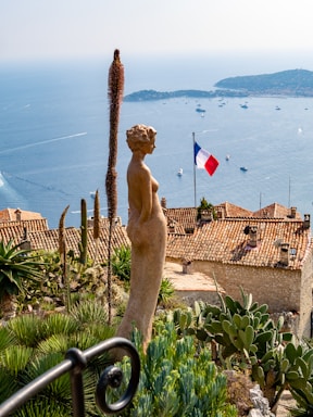 woman brown statue with view of France flag during daytime
